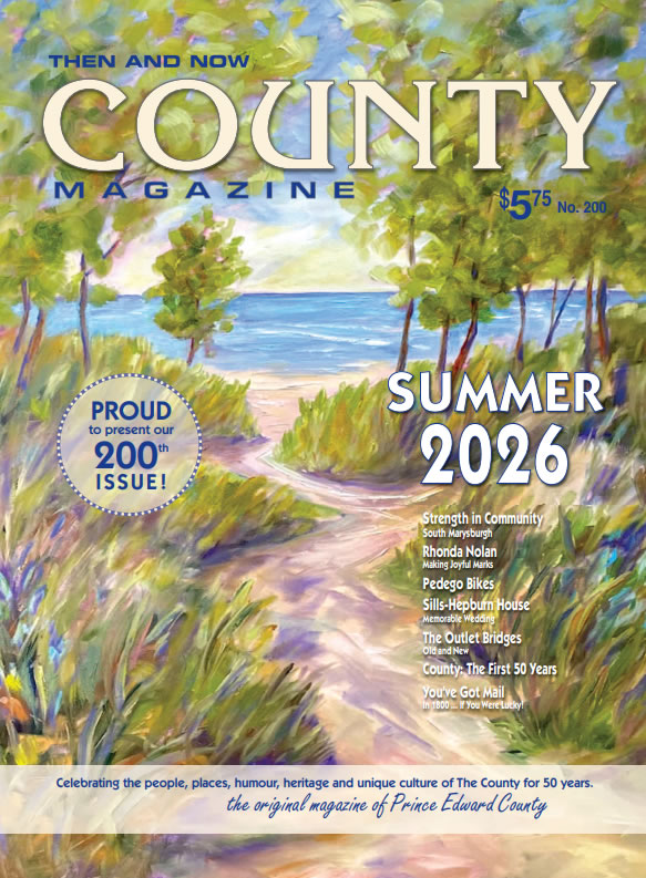 Colorful painting of a beach path through dunes toward the sea, overlaid with 'County Magazine' and 'Summer 2026' on a summer issue cover.