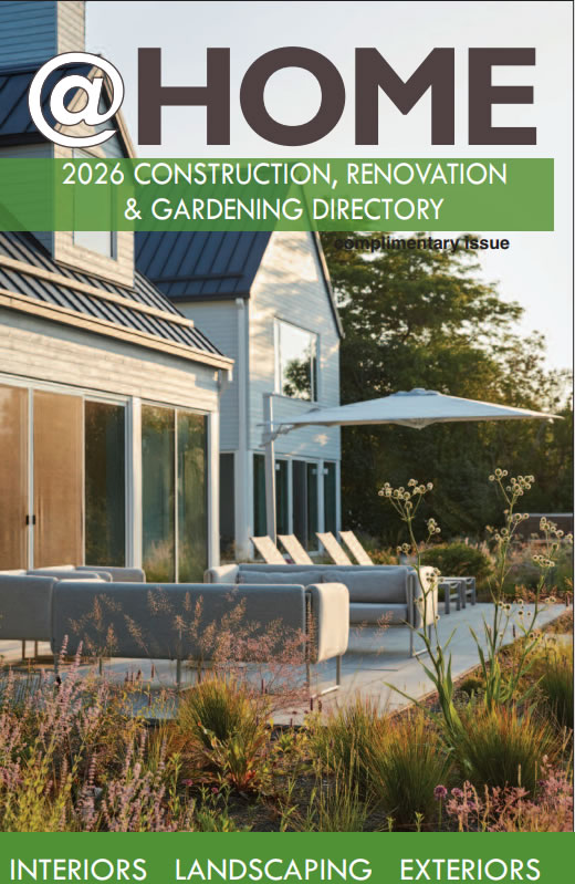 Cover image for @HOME magazine: a modern house with a spacious patio, outdoor seating, and a landscaped garden under a clear sky; the green banner proclaims '2026 Construction, Renovation & Gardening Directory'. The bottom edge highlights 'Interiors, Landscaping, Exteriors'.